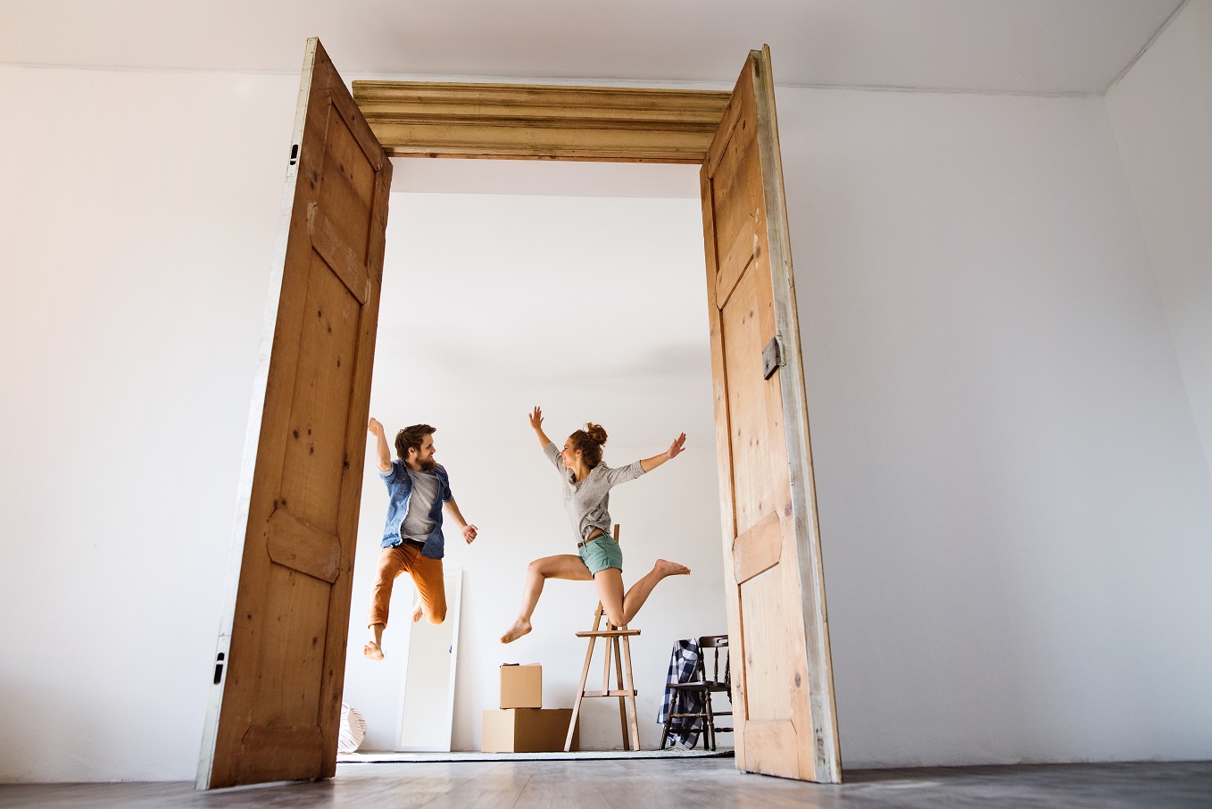 Young couple moving in a new house, jumping up high.